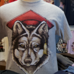 Branded merchandise for sale, including a t-shirt with a wolf wearing a mortarboard.
