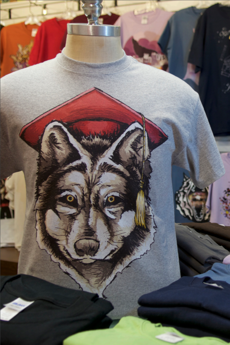 Branded merchandise for sale, including a t-shirt with a wolf wearing a mortarboard.