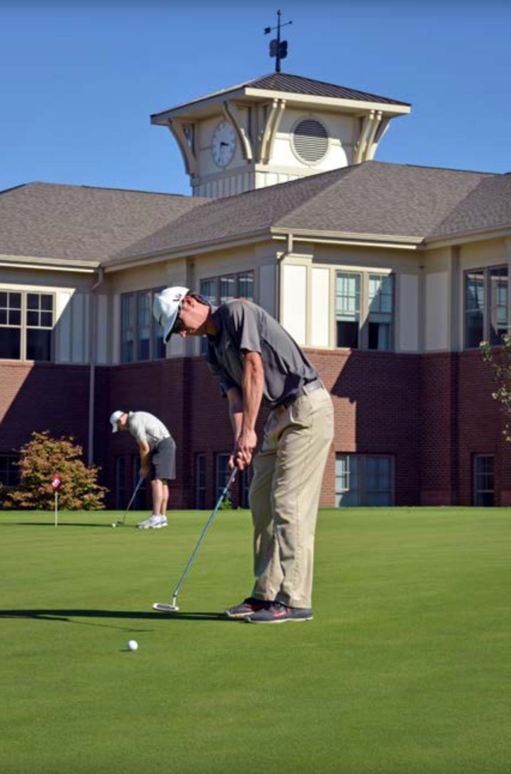 A golfer practices putting at the Lonnie Poole Golf Course.