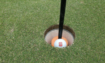 Golf ball inside a hole on the Lonnie Poole Golf Course.