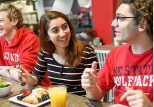 This is a photo of students eating together at an NC State Dining location.